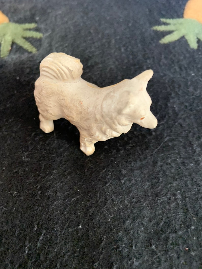 Miniature Pomeranian dog collectible. A small white LINEOL dog figurine with a fluffy tail. The dog is standing on all four legs and has its head tilted to the side.