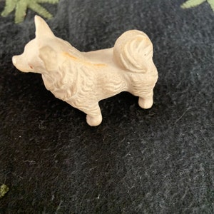 Vintage toy dog figurine close-up. A small white LINEOL dog figurine with a curly tail.