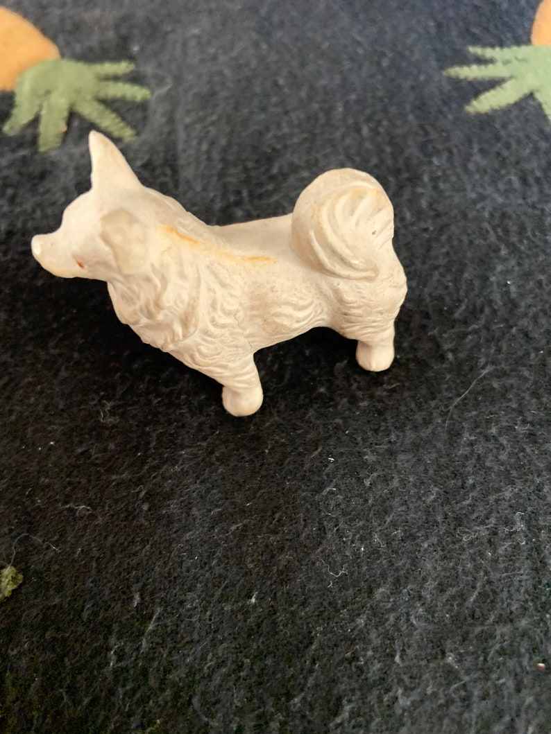 Vintage toy dog figurine close-up. A small white LINEOL dog figurine with a curly tail.