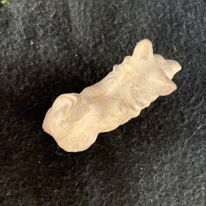 Collectible miniature dog figurine. A small, white, LINEOL figurine of a dog lying down. The figurine is detailed with fur and has a realistic appearance.