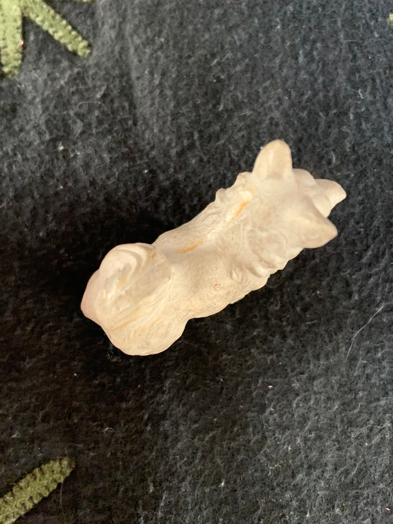 Collectible miniature dog figurine. A small, white, LINEOL figurine of a dog lying down. The figurine is detailed with fur and has a realistic appearance.
