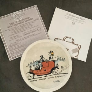 May include: A white ceramic plate with a colorful illustration of a red car with two people inside. The car is driving through a countryside scene with the text "walking through merrie Englande".