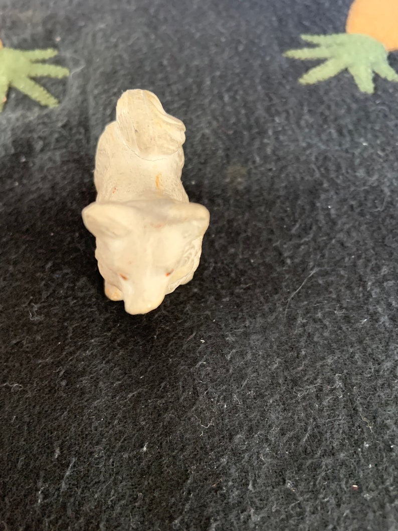 LINEOL animal figurine 2 inch. A small white LINEOL figurine of a dog sitting on its hind legs with its head tilted down. The dog has a long tail that curls up over its back.