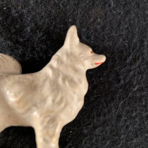 LINEOL composite plastic dog figure. A white LINEOL figurine of a dog with red painted details on the nose and mouth. The dog is standing on all four legs and has a fluffy tail.