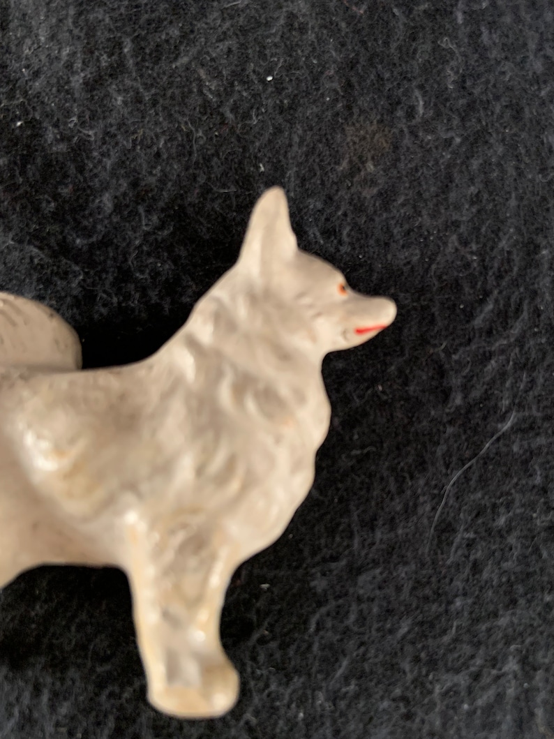 LINEOL composite plastic dog figure. A white LINEOL figurine of a dog with red painted details on the nose and mouth. The dog is standing on all four legs and has a fluffy tail.