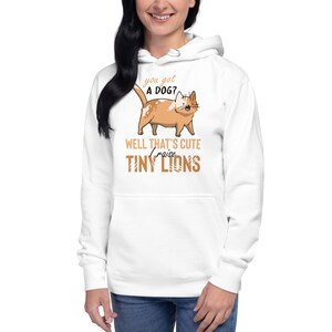 May include: White hoodie with a cartoon cat and the text "you got a dog? well that's cute I raise tiny lions".