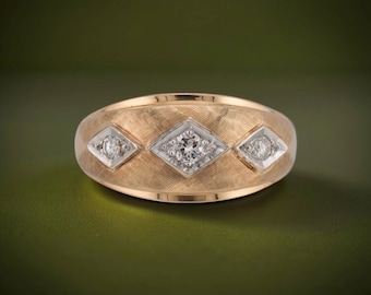 May include: A rose gold ring featuring a textured, cross-hatched surface with three diamond-set white gold diamond-shaped inlays. The central inlay is larger than the two flanking inlays, each containing a single round, clear, faceted gemstone.