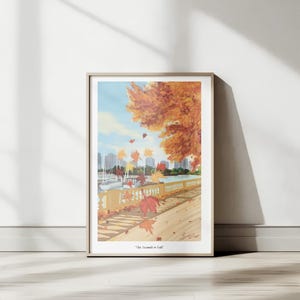 Op de afbeelding: Ingelijste kunstdruk met een herfsttafereel met een waterkant, zeilboten en een stadsgezicht op de achtergrond. Het kunstwerk toont een grote boom met oranje bladeren en vallende bladeren. De tekst "The Season is Fall" staat onderaan.