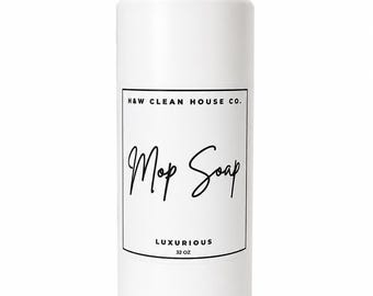 May include: A white plastic bottle with a screw-top cap featuring a rectangular label. The label text reads H&W CLEAN HOUSE CO. at the top, Mop Soap in a script font in the center, and LUXURIOUS 32 OZ at the bottom in black lettering.