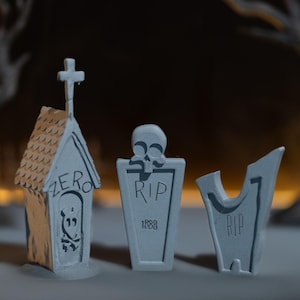Puede incluir: Tres lápidas grises en miniatura con las palabras "ZERO" y "RIP". Una lápida tiene forma de casa con una cruz encima. Las otras dos lápidas tienen una calavera y el año 1888.