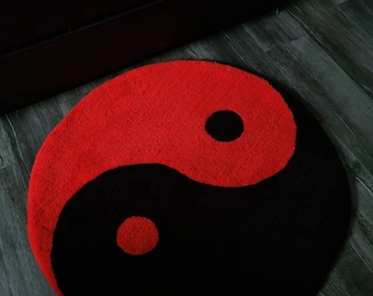 May include: A black and red yin yang symbol rug. The rug is round and has a soft, fuzzy texture.