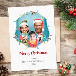 Op de afbeelding: Een kerstkaart met een familieportret, inclusief twee honden met kerstmutsen. De kaart heeft een blauwe achtergrond met lichtjes en de tekst "Merry Christmas" en "From The Johnsons Family 2025".