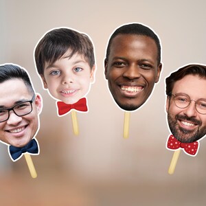 May include: Four face cutouts on sticks, each with a different person's face. One man wears glasses and a blue bow tie. Another has a red bow tie. The third has a red bow tie with white polka dots. The fourth is a young boy with a red bow tie.
