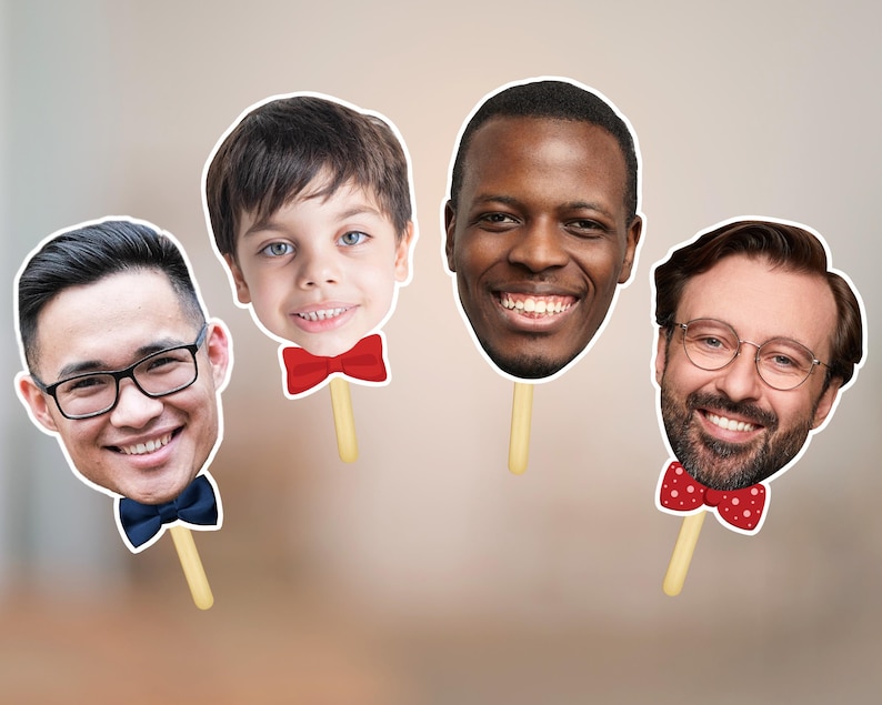 May include: Four face cutouts on sticks, each with a different person's face. One man wears glasses and a blue bow tie. Another has a red bow tie. The third has a red bow tie with white polka dots. The fourth is a young boy with a red bow tie.