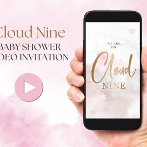 Puede incluir: Un fondo de acuarela rosa y blanco con una fuente de escritura dorada en cursiva que dice "We are on Cloud Nine". Una mano sostiene un teléfono inteligente que muestra la misma imagen. El icono del botón de reproducción es visible en la pantalla.