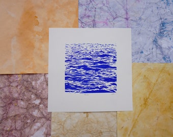 May include: A blue and white print of a wave pattern. The print is on white paper and has the word "Waves" printed below the image.
