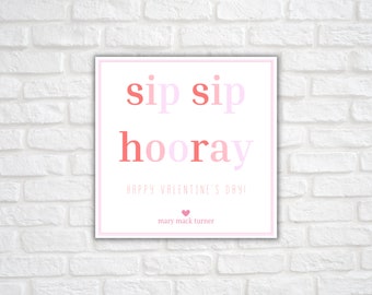 May include: A white card with pink and red text that reads "sip sip hooray happy valentine's day! mary mack turner" with a pink heart symbol.