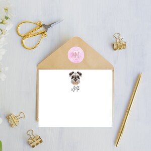 May include: A white card with a gray and white dog illustration and the text "SJM" in cursive. The card is in a brown envelope with a pink circle sticker with the letters "MM" in a brown circle.