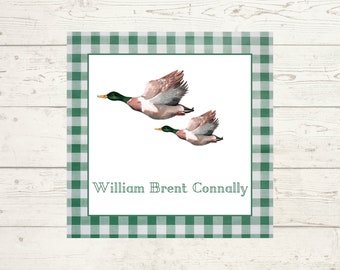 May include: A white card with a green and white gingham border. Two ducks are flying in the center of the card. The text "William Brent Connally" is printed below the ducks.