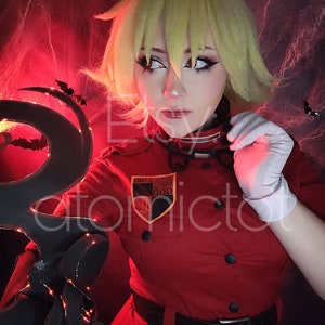 Può includere: Una donna in un costume da cosplay rosso con una toppa nera e dorata che dice "GOD", "HELLSING" e "DIVISION IV". Indossa una cintura nera e guanti bianchi. Lo sfondo è rosso scuro con ragnatele nere.