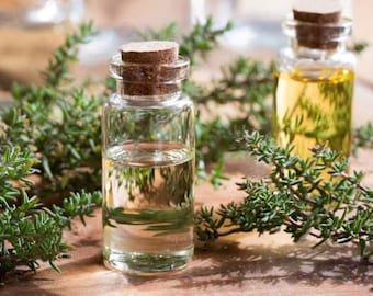 May include: Two clear glass bottles with cork tops filled with a light yellow liquid. The bottles are surrounded by sprigs of green thyme.