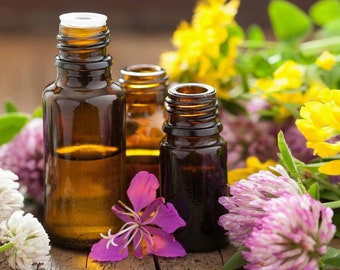May include: Three amber glass bottles with essential oils, surrounded by purple, white, and yellow flowers.