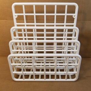 May include: A stack of four white plastic storage baskets. Each basket has a rectangular shape with a grid-like pattern. The baskets are designed to be stacked on top of each other, creating a multi-tiered storage solution.