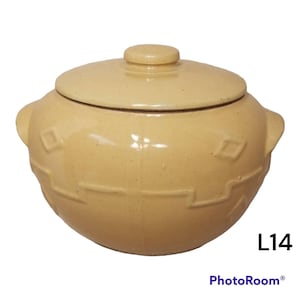 May include: A yellow ceramic crock pot with a lid and a woven pattern. The crock pot has two small handles on the sides. The crock pot is labeled "L14".