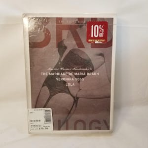 May include: A Criterion Collection DVD of Rainer Werner Fassbinder's films, including "The Marriage of Maria Braun," "Veronika Voss," and "Lola." The cover features a sepia-toned image and the text "10% Off." The DVD is sealed in plastic.