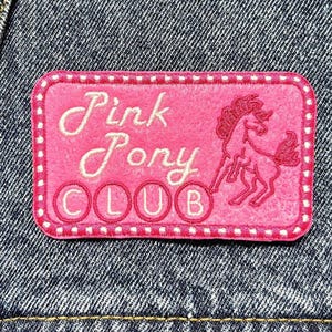 May include: Pink Pony Club embroidered patch with a pink background, white stitching, and a white outline. The patch features a white horse with a pink mane and tail.