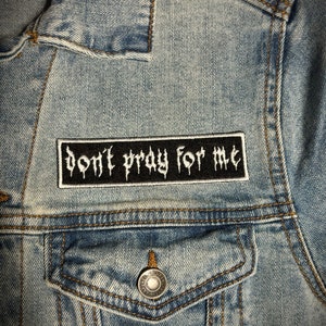 May include: A light blue denim jacket with a black patch that reads "Don't pray for me".