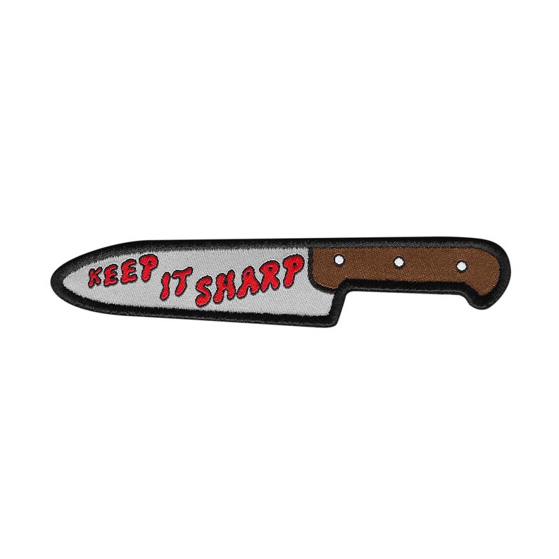 Op de afbeelding: Een geborduurde patch van een mes met de tekst "KEEP IT SHARP" in rood.