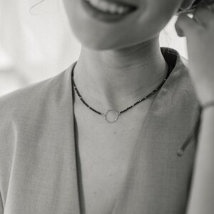 This black and white photo shows the shape of the sterling silver circle and the fine, delicate and minimalist design of this jewelry that the woman is wearing.