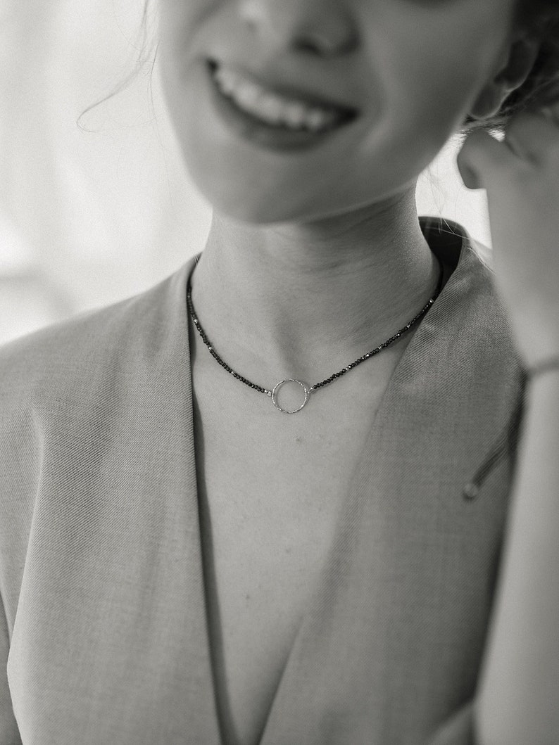 This black and white photo shows the shape of the sterling silver circle and the fine, delicate and minimalist design of this jewelry that the woman is wearing.