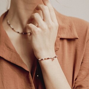 Our model wears on her wrist the garnet bracelet, which also combines it with her matching choker, also with red garnet pendant and pyrite and agate beads. The model is wearing a reddish blouse perfect to combine with our garnet bracelet.