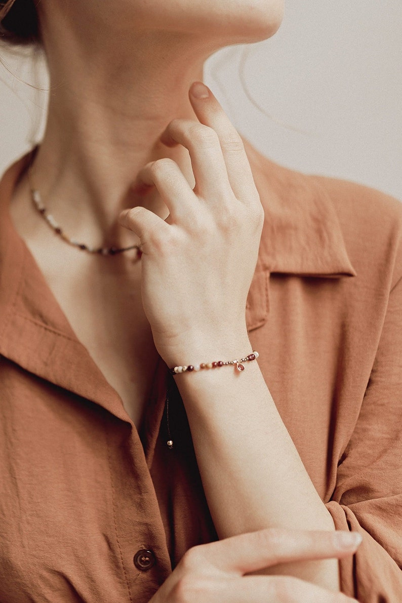 Our model wears on her wrist the garnet bracelet, which also combines it with her matching choker, also with red garnet pendant and pyrite and agate beads. The model is wearing a reddish blouse perfect to combine with our garnet bracelet.