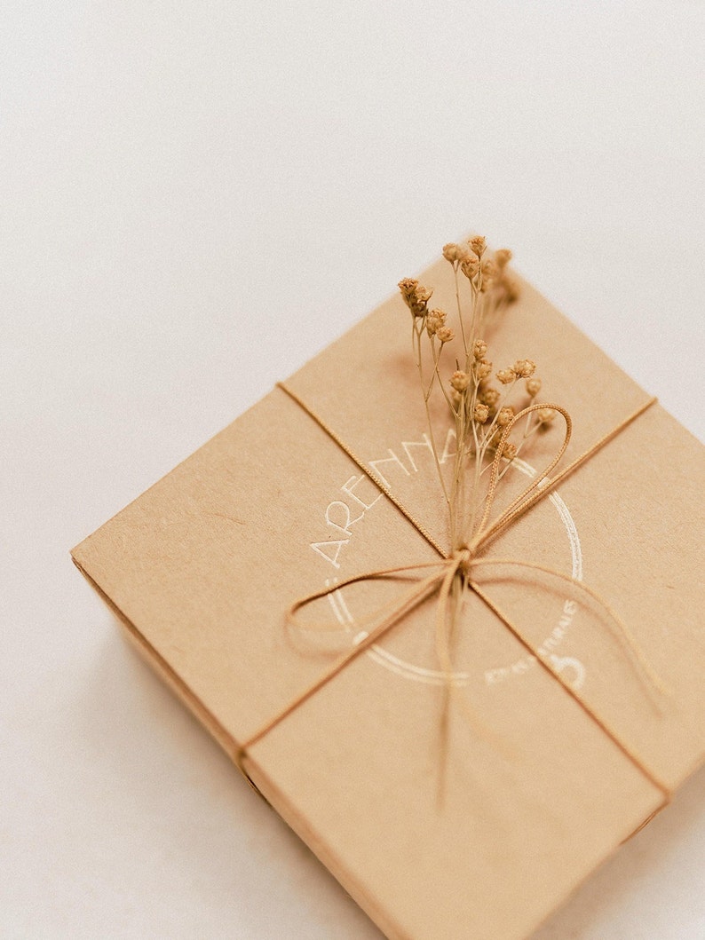 Our recycled cardboard box that we use as packaging, totally sustainable, and with our brand logo in gold, all decorated with tiny and delicate dried flowers. This little box and its jewel inside make a dainty and genuine gift for her.