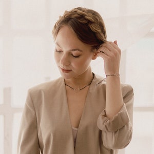 The woman shows the bracelet and the silver circle choker in a bohemian and delicate atmosphere.