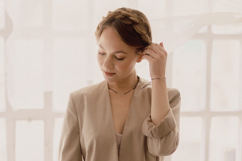 The woman shows the bracelet and the silver circle choker in a bohemian and delicate atmosphere.