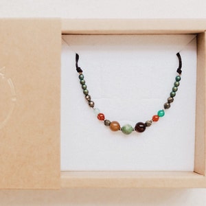 The boho chic gemstone bracelet is seen inside its cardboard box, ready to present as a boho, bohemian and colorful gift for her.