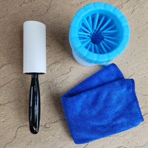 May include: A blue dog grooming brush with a white handle, a white lint roller, and a blue microfiber cloth.