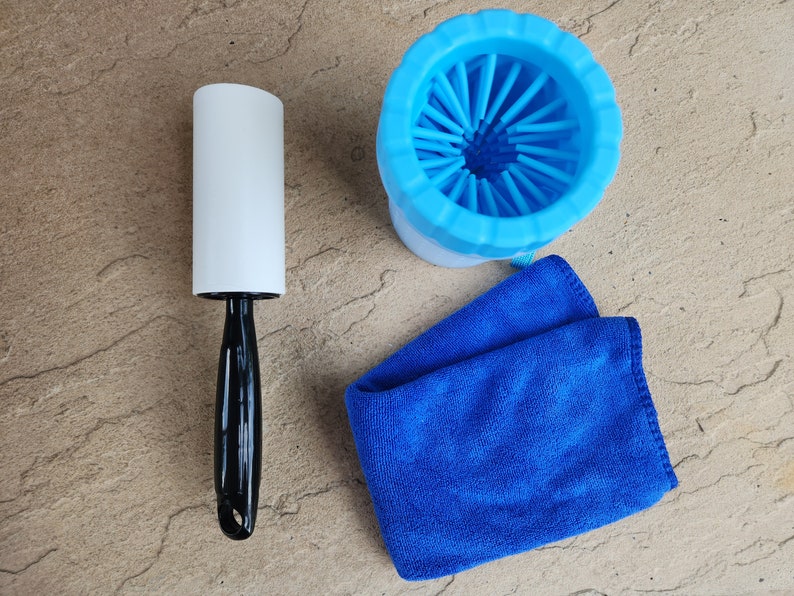 May include: A blue dog grooming brush with a white handle, a white lint roller, and a blue microfiber cloth.