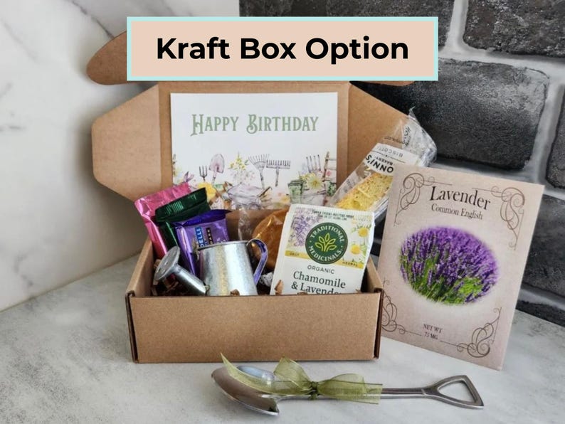May include: A kraft box labeled "Kraft Box Option" contains a birthday card, tea packets, a small watering can, and a packet of lavender seeds. A small shovel-shaped bottle opener rests in front of the box. The card reads "Happy Birthday."