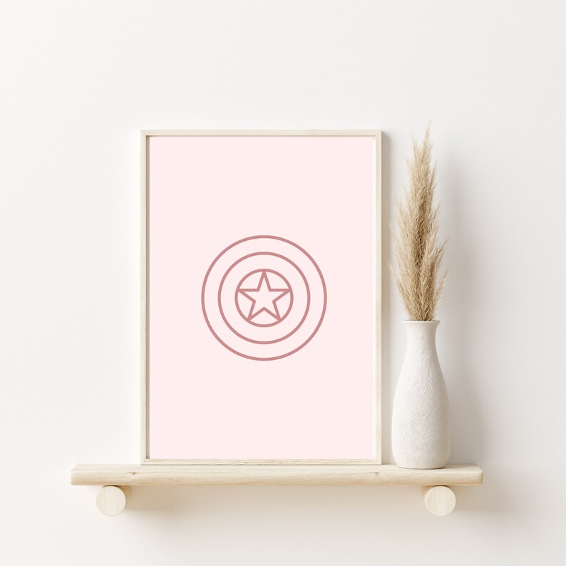 K&ouml;nnte beinhalten: Ein rosa gerahmter Druck mit wei&szlig;em Hintergrund und einer rosa Umrandung eines Sterns in einem Kreis. Der Druck befindet sich auf einem Holzregal mit einer getrockneten Graspflanze in einer wei&szlig;en Vase.
