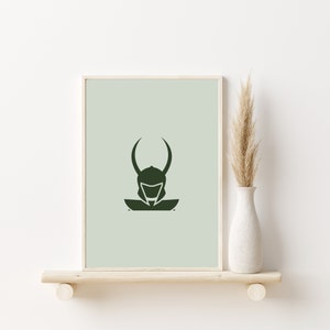 K&ouml;nnte beinhalten: Eine minimalistische gr&uuml;ne Silhouette einer Figur, die einen Helm mit H&ouml;rnern auf einem hellgr&uuml;nen Hintergrund tr&auml;gt. Das Bild ist gerahmt und auf einem Regal mit einer getrockneten Graspflanze in einer wei&szlig;en Vase ausgestellt.