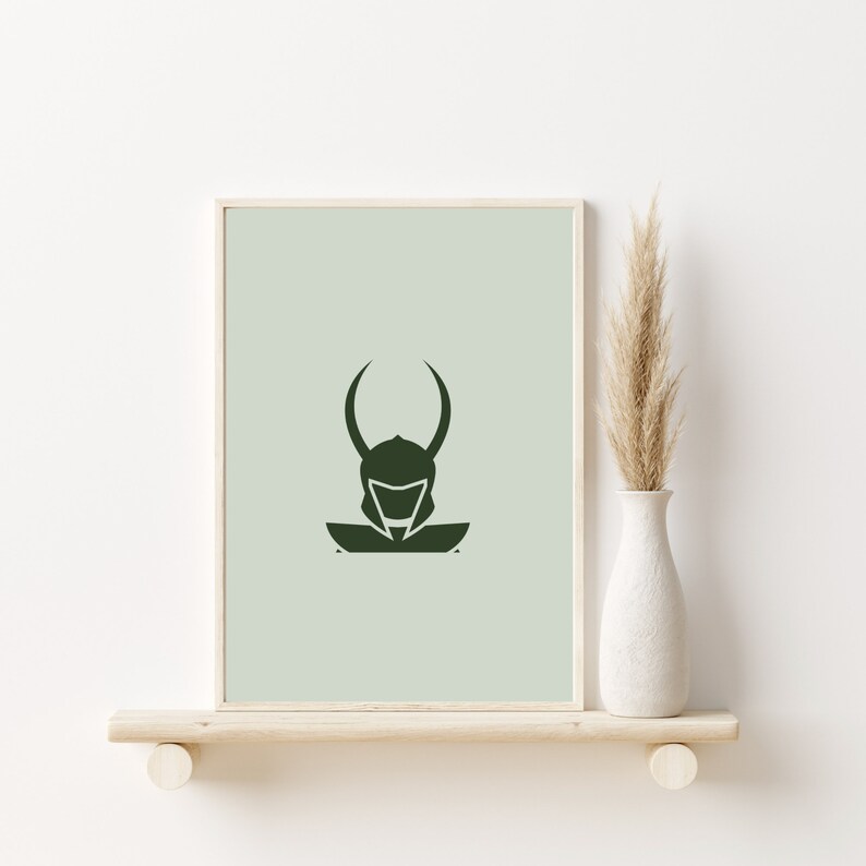 K&ouml;nnte beinhalten: Eine minimalistische gr&uuml;ne Silhouette einer Figur, die einen Helm mit H&ouml;rnern auf einem hellgr&uuml;nen Hintergrund tr&auml;gt. Das Bild ist gerahmt und auf einem Regal mit einer getrockneten Graspflanze in einer wei&szlig;en Vase ausgestellt.