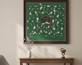 May include: A framed artwork featuring a peacock design with a green background, white flowers, and two birds. The artwork hangs above a wooden console table with a curved apron. A gray chair and a potted plant are also in the room.