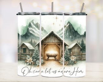 May include: A white tumbler with a watercolor design featuring a nativity scene with a wooden stable, mountains, and the text "Oh come let us adore Him." Includes a silver lid and straw.
