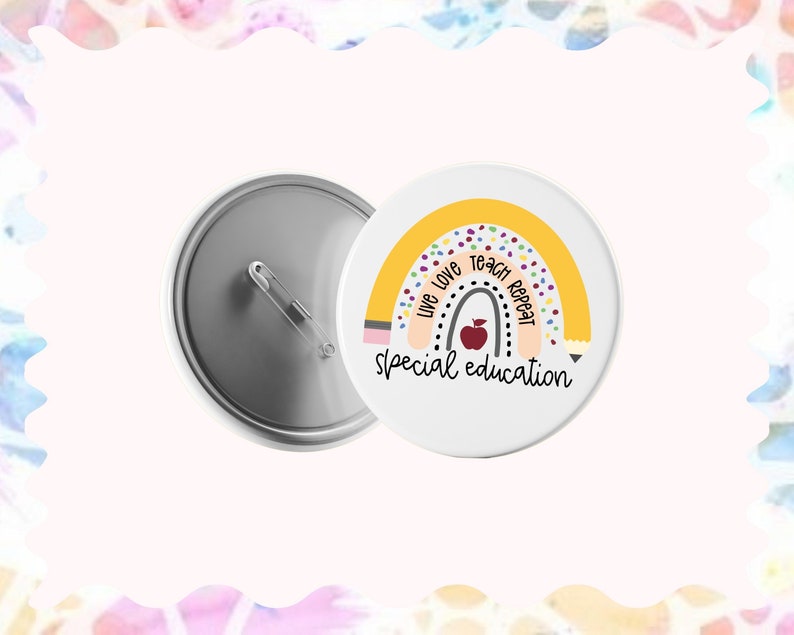 May include: A white button with a yellow rainbow design and the text "Live Love Teach Repeat Special Education". The rainbow has a pencil design on each end and a red apple in the center.