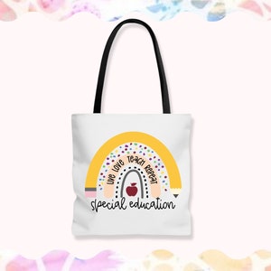 May include: White tote bag with a rainbow design and the text "Live Love Teach Repeat Special Education". The rainbow is yellow with multi-colored dots and a red apple in the center.